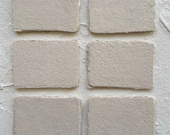 May include: Six rectangular cards made of thick, light beige paper with rough, deckled edges. The cards are arranged in two columns of three, displaying a textured, fibrous surface characteristic of handmade paper, with a neutral, earthy tone.