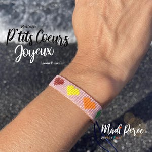 May include: A pink loom bracelet with a pattern of colorful hearts. The bracelet is labeled "P'tits Coeurs Joyeux" and "Loom Bracelet".