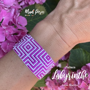 Könnte beinhalten: Ein Loom-Armband mit einem geometrischen Muster in Weiß und Magenta. Das Armband wird am Handgelenk getragen und ist von rosa Blüten umgeben. Der Text "Madi Perec Jewelry Pop!" sowie "Pattern Labyrinthe Loom Bracelet" sind sichtbar.
