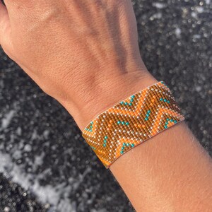 May include: A beaded bracelet with a geometric pattern in shades of brown, orange, and turquoise.