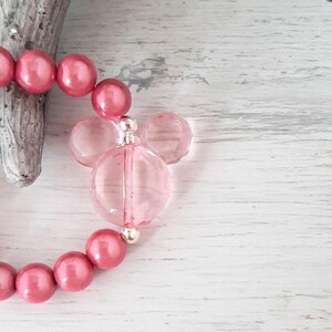 May include: A pink beaded bracelet with a clear pink Mickey Mouse charm.
