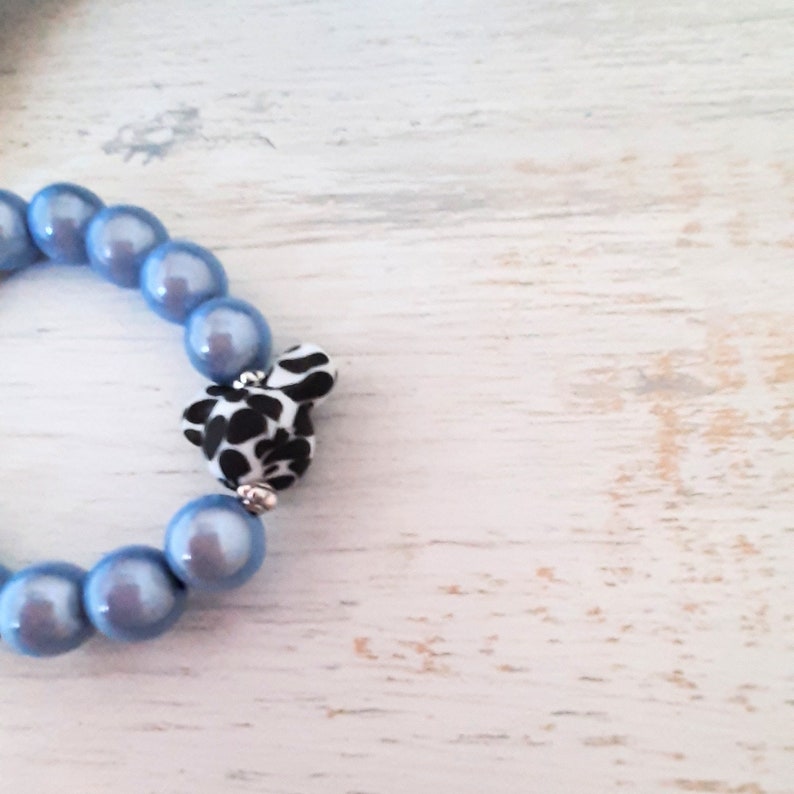 May include: A blue beaded bracelet with a black and white patterned charm.
