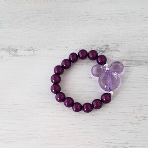 May include: A purple beaded bracelet with a purple Mickey Mouse charm.