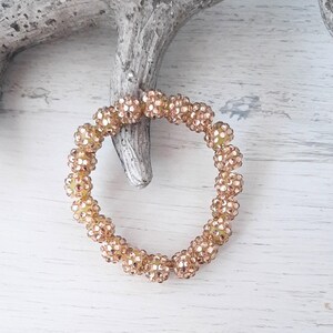 Könnte beinhalten: Ein goldfarbenes Armband mit runden, glitzernden Perlen. Die Perlen sind mit kleinen, klaren Strasssteinen besetzt.