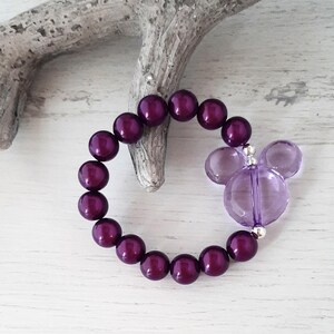 May include: A purple beaded bracelet with a clear purple Mickey Mouse charm.