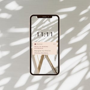 Op de afbeelding: Een smartphone-scherm dat de tijd 11:11 weergeeft met een notificatieherinnering voor "Wealth Wiring Hypnosis" die "Herprogrammeer je geest voor moeiteloze overvloed" luidt.