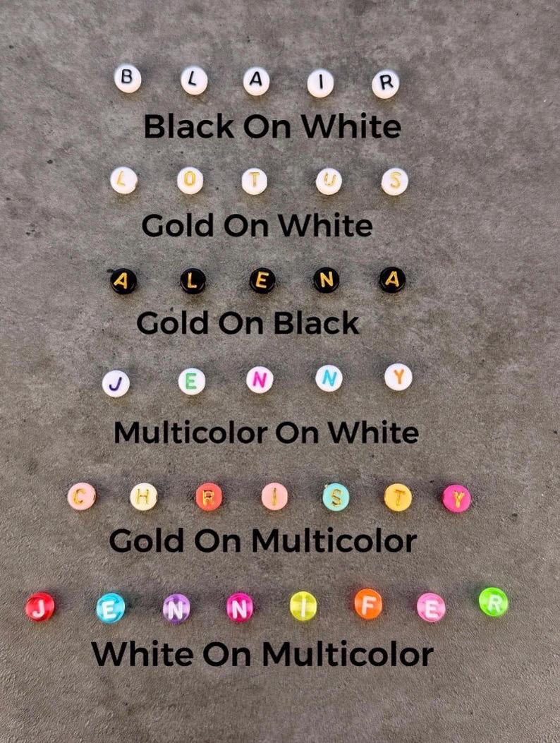 May include: Six rows of round alphabet beads displaying various color combinations: black letters on white, gold on white, gold on black, multicolor on white, gold on multicolor, and white on multicolor. Each row includes text labels identifying the style.