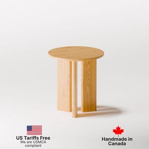 May include: A small, round wooden side table with a light oak finish. The table has a circular top and three vertical supports. The table is approximately 18 inches in height and 16 inches in diameter.