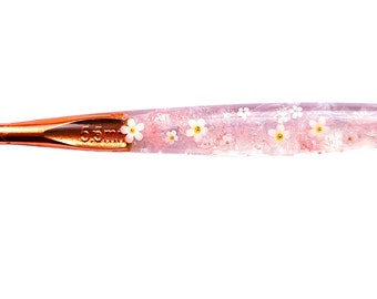 Beautiful crochet hook with little white flowers with a pink swirl effect.