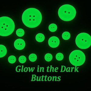 May include: A selection of luminous green buttons in different sizes, set against a black backdrop. The buttons feature two or four holes. The words "Glow in the Dark Buttons" are written in green at the bottom.