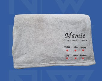 Puede incluir: Una manta de forro polar blanca con el texto "Mamie & ses petits coeurs" y los nombres Theo, Lea, Tom, Mae, Liam y Emma con corazones rojos.