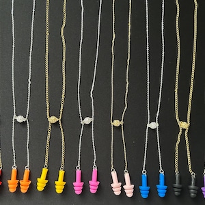 Peut inclure: Ensemble de 10 paires de bouchons d'oreilles avec une chaîne et un petit charme. Les bouchons d'oreilles sont disponibles dans une variété de couleurs, notamment le rouge, l'orange, le jaune, le rose, le bleu, le violet et le noir.
