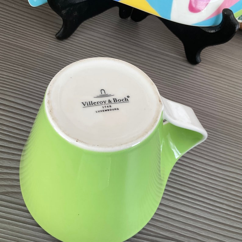 May include: A green ceramic mug with a white handle. The mug has the Villeroy & Boch logo and the text "1748 Luxembourg" on the bottom.