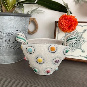 May include: White ceramic planter with green and white striped handles. The planter is decorated with colourful polka dots.