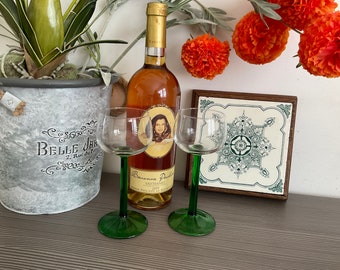 May include: Two wine glasses with green stems and a bottle of wine in the background. The bottle is labelled with the text "Baronnie Paille" and "Sauternes 2009".