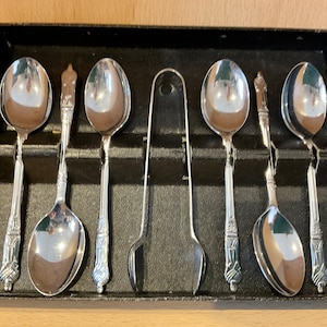 Peut inclure: Un ensemble de six cuillères à café en argent et une pince à sucre dans un coffret doublé de velours noir.