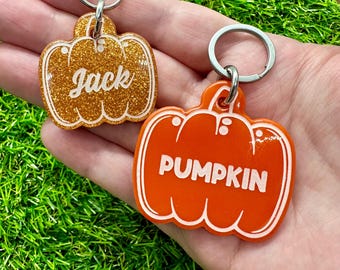 May include: Two pumpkin-shaped keychains. One is gold glitter with the name "Jack" in white. The other is orange with the word "PUMPKIN" in white. Both have silver key rings.