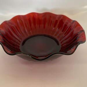 Peut inclure: Un bol en verre rouge foncé avec un bord festonné et un motif côtelé.