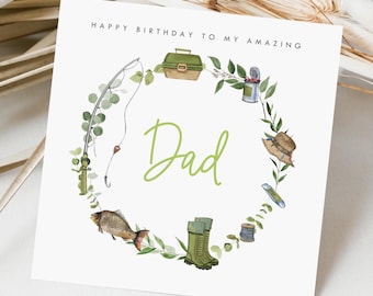 May include: A white card with green text that reads "Happy Birthday to my amazing Dad". The card is decorated with a green wreath of leaves and fishing-themed illustrations, including a fishing rod, tackle box, fish, boots, and a can of worms.