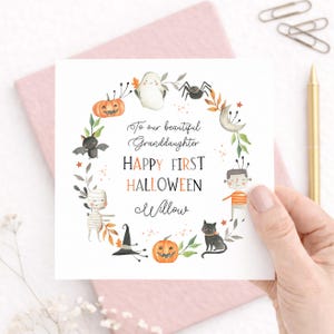Personalised first Halloween card for a granddaughter featuring sweet Halloween characters including a ghost, pumpkin, mummy, bat, spider and black cat. The card reads Happy First Halloween and is personalised for a beautiful granddaughter or any relation