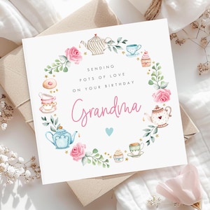 May include: A white card with a pink and blue watercolour illustration of teacups, teapots, cupcakes, and flowers. The text on the card reads "Sending pots of love on your birthday Grandma".