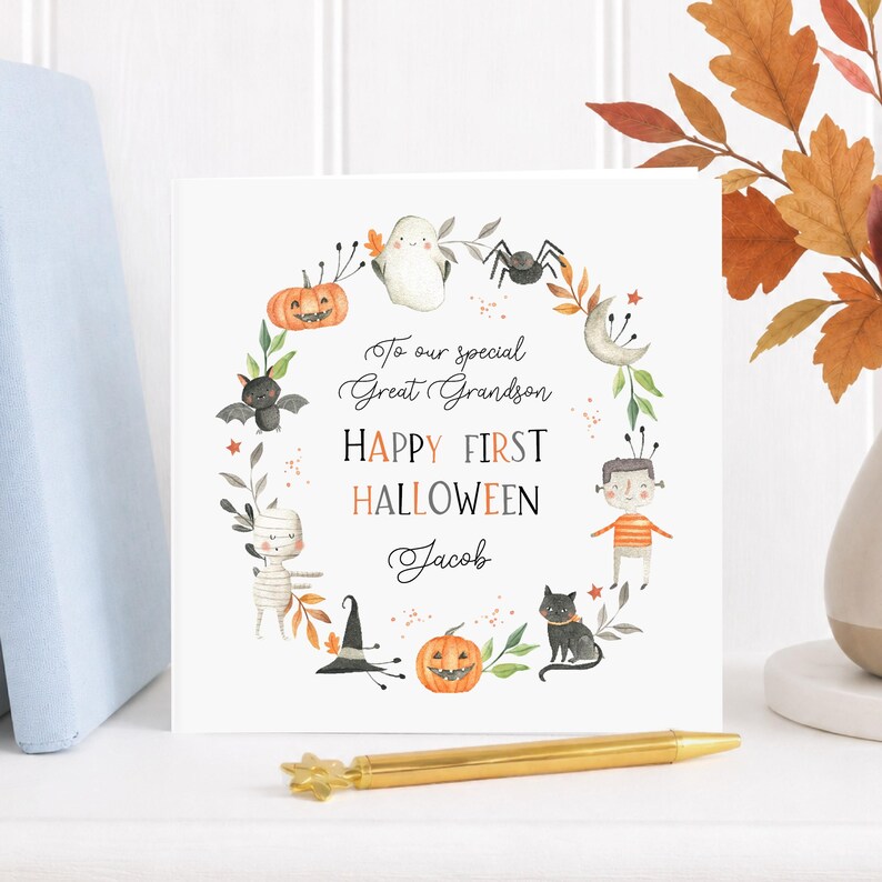 Cute personalised first Halloween card for a great grandson with a friendly ghost, smiling pumpkins, mummy, bat, spider, black cat and autumn leaves. The Happy First Halloween card is personalised with the child's name