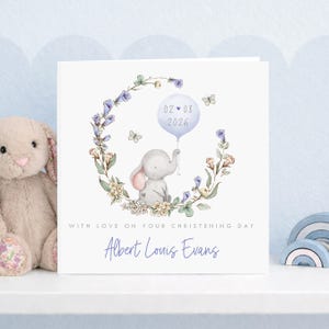 Personalised christening card for baby girl or boy featuring a cute little elephant illustration holding a balloon surrounded by a floral wreath. Perfect keepsake card suitable for christening, baptism, dedication day and more.
Custom name and date, pink or blue options. Printed on quality 300gsm lightly textured cardstock, measures 148 x 148mm and is supplied with a blank recycled kraft envelope.
