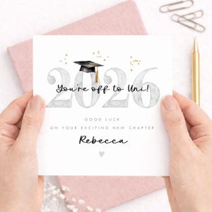 May include: A white greeting card featuring the text 2026 with a black graduation cap and gold stars. The card includes the printed text You're off to Uni!, GOOD LUCK ON YOUR EXCITING NEW CHAPTER, and the name Rebecca, finished with a small grey heart.