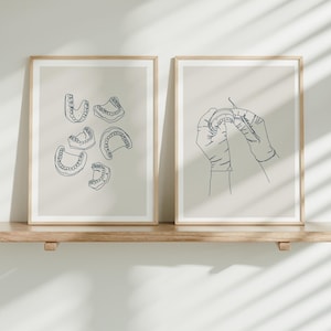 May include: Two framed illustrations of dental imagery. The first illustration shows a set of teeth in various positions. The second illustration shows a pair of hands holding a tooth.