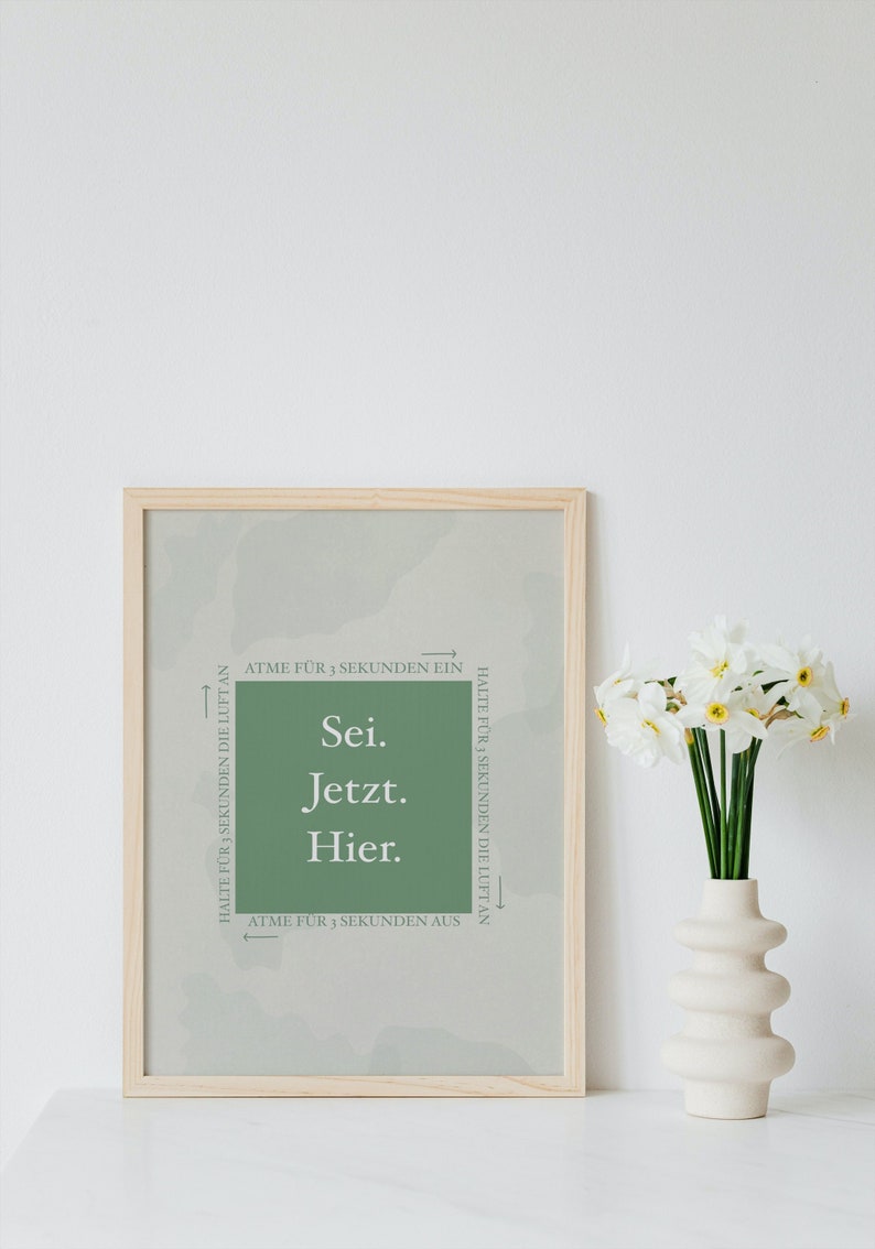 K&ouml;nnte beinhalten: Ein gerahmter Druck mit gr&uuml;nem Hintergrund und wei&szlig;em Text, der "Sei. Jetzt. Hier." lautet. Der Text ist von Pfeilen umgeben, die in entgegengesetzte Richtungen zeigen, mit den Worten "Atme f&uuml;r 3 Sekunden ein" und "Halte f&uuml;r 3 Sekunden die Luft an".