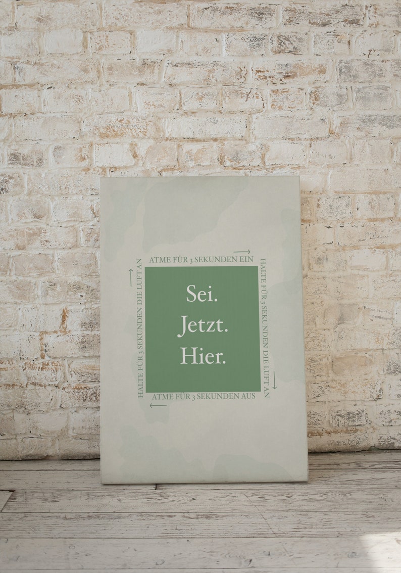 K&ouml;nnte beinhalten: Ein gr&uuml;ner Leinwanddruck mit dem Text "Sei. Jetzt. Hier." und Anweisungen zum Ein- und Ausatmen f&uuml;r 3 Sekunden und Anhalten des Atems f&uuml;r 3 Sekunden.