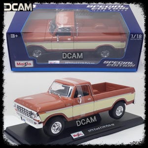 May include: A brown and beige 1979 Ford F150 pickup truck diecast model car in a 1/18 scale. The truck is on a black display base with the Maisto logo and the words "DCAM" and "1979 Ford F150 Pick-up".