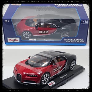 May include: A red and black Bugatti Chiron die-cast model car, 1/18 scale, displayed on a black base. The model is in a clear plastic case with the text "SPECIAL EDITION" and "DCAM". The Maisto logo is visible.