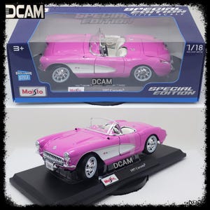 May include: A pink 1957 Corvette die-cast model car in a display case. The car is a 1/18 scale model and is part of the DCAM Special Edition series. The box features the Maisto logo and the words "Special Edition".