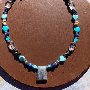 May include: A necklace made with various blue, turquoise, and brown stones, including a large grey labradorite pendant.