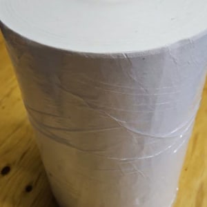 May include: A large roll of white paper wrapped in clear plastic.