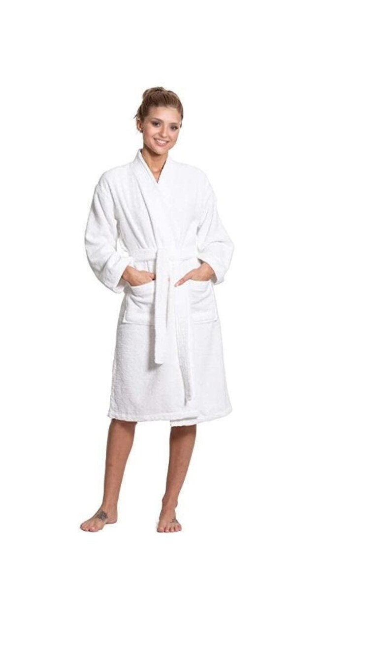 Puede incluir: Una bata de ba&ntilde;o blanca con cuello chal y cintur&oacute;n de atar. La bata tiene dos bolsillos en la parte delantera.