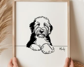 Könnte beinhalten: Ein gerahmter Druck mit einer minimalistischen Strichzeichnung eines Hundes. Das Kunstwerk ist in Schwarz und Weiß gehalten, wobei die Form des Hundes durch eine durchgehende Linie dargestellt wird. Der Hund hat schwarzes Fell auf Kopf und Ohren, mit einem hellen Gesicht. Der Name "Monty" ist in Schrift geschrieben.