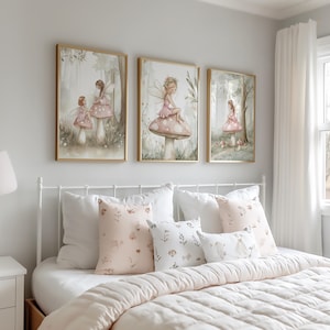 May include: Three framed watercolor art prints featuring fairies in a whimsical forest setting. The prints have gold frames and depict fairies on mushrooms. The bed below has white bedding and decorative pillows with floral patterns.