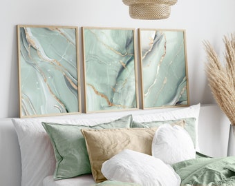 May include: Three framed prints with abstract green and gold marble patterns. The prints are arranged horizontally on a white wall above a bed with white and green pillows.