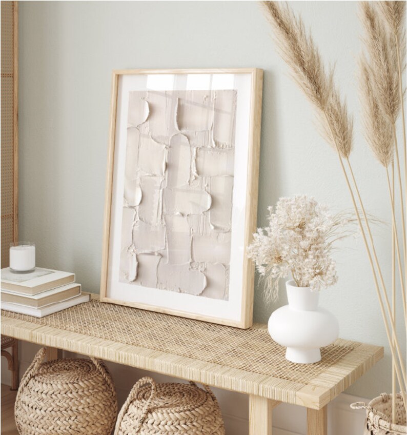 Peut inclure: Un banc en bois clair avec un dessus en rotin tiss&eacute;, deux paniers tiss&eacute;s et un vase en c&eacute;ramique blanche avec des fleurs blanches s&eacute;ch&eacute;es. Un tableau abstrait encadr&eacute; avec un fond beige est accroch&eacute; au mur derri&egrave;re le banc.