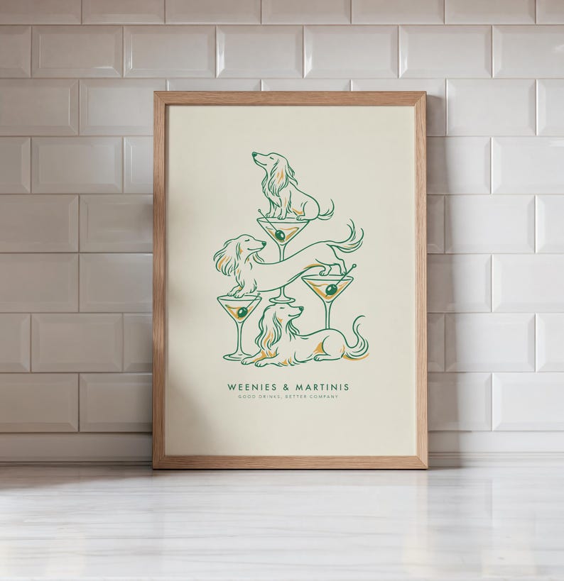 May include: A framed art print featuring three long-haired dachshunds interacting with martini glasses. The illustration uses green and gold lines on a cream background. The text reads WEENIES & MARTINIS and GOOD DRINKS, BETTER COMPANY.