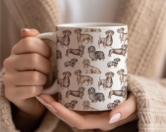May include: White ceramic mug featuring a repeating pattern of dachshund illustrations in various poses and colors. The dachshunds are depicted in shades of brown, tan, and black. The mug has a white handle and is held by a person.
