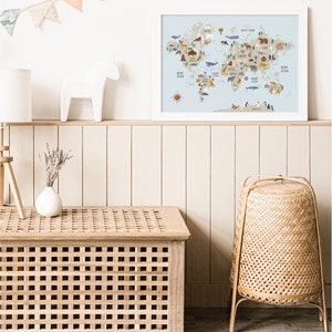 Peut inclure: Une carte du monde bleu clair avec des illustrations d'animaux de diff&eacute;rents continents. La carte est encadr&eacute;e et accroch&eacute;e &agrave; un mur blanc au-dessus d'une &eacute;tag&egrave;re en bois avec une figurine de cheval en c&eacute;ramique blanche.
