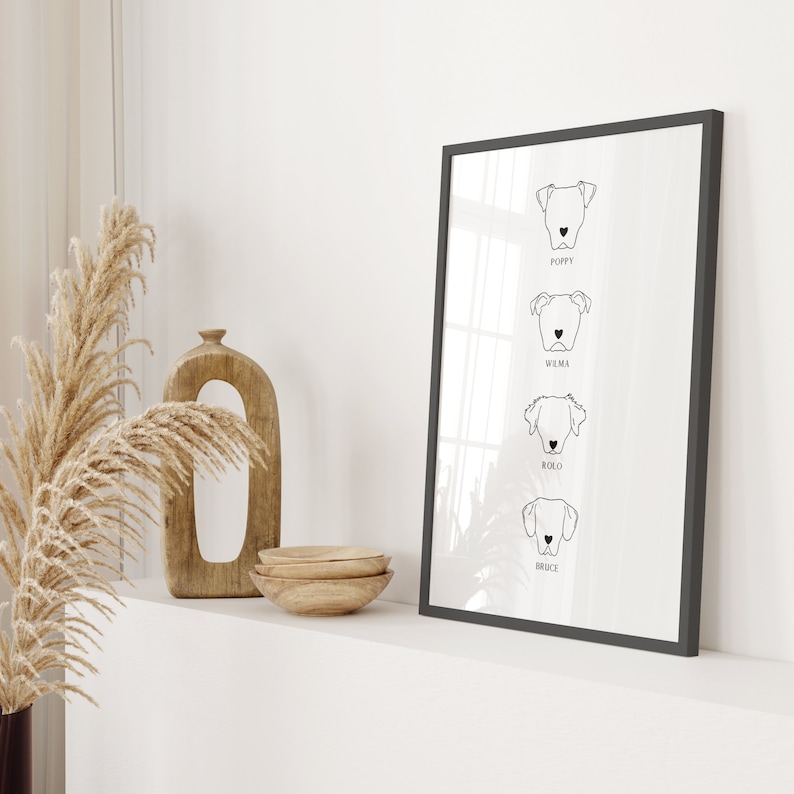 May include: Black and white line art print of four dog portraits with their names below each portrait: Poppy, Wilma, Rollo, and Bruce. The print is framed in a black frame and is hanging on a white wall.