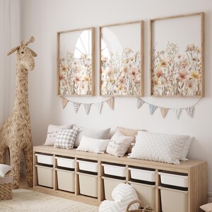 Puede incluir: Un banco de madera clara con un conjunto de contenedores de almacenamiento blancos. El banco est&aacute; decorado con almohadas y una guirnalda de banderas. Tres impresiones enmarcadas de dise&ntilde;os florales de acuarela cuelgan en la pared sobre el banco.