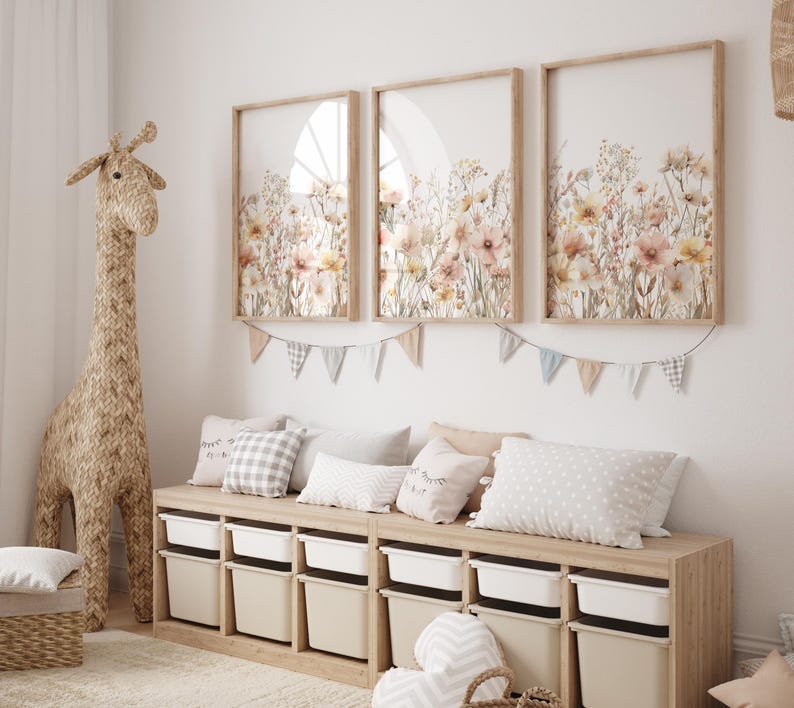 Puede incluir: Un banco de madera clara con un conjunto de contenedores de almacenamiento blancos. El banco est&aacute; decorado con almohadas y una guirnalda de banderas. Tres impresiones enmarcadas de dise&ntilde;os florales de acuarela cuelgan en la pared sobre el banco.