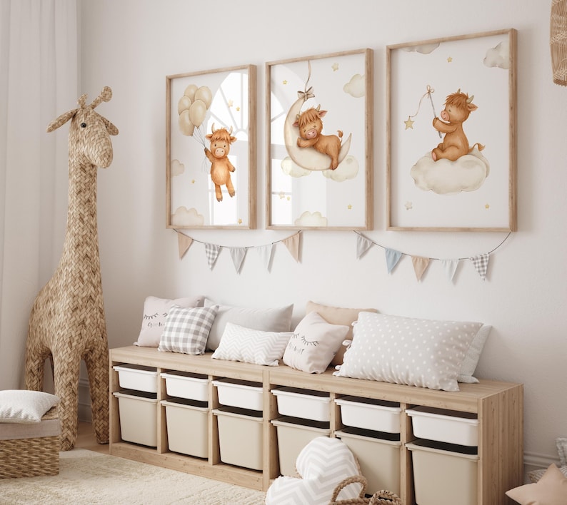 K&ouml;nnte beinhalten: Drei gerahmte Kunstdrucke f&uuml;r das Kinderzimmer mit Aquarellillustrationen eines Highland-K&auml;lbchens. Ein Kalb h&auml;lt Ballons, ein anderes ruht auf einem Mond, und das dritte sitzt auf einer Wolke und h&auml;lt einen Stern. Die Drucke sind in einem Kinderzimmer.