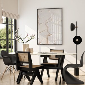 May include: A modern dining room with a white marble table, black chairs, and a black floor lamp with a round shade. A vase with a branch of pink flowers sits on the table.