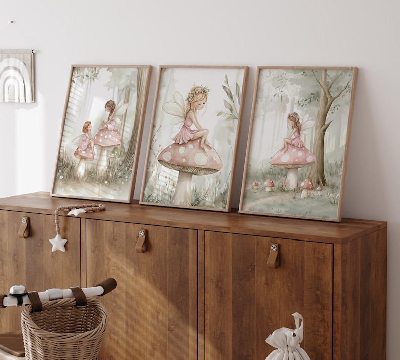 May include: Three framed watercolor prints featuring fairies in a whimsical forest setting. Each print showcases a fairy in a pink dress, perched on a mushroom. The artwork has a soft, pastel color palette with a dreamy, ethereal quality.
